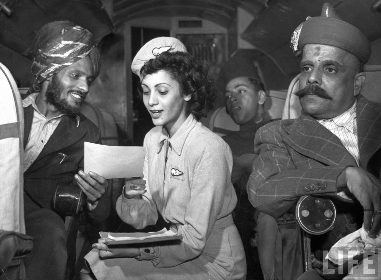 Air India flight attendant Monica Gilbert (C) showing flight report to Sikh passenger during trip from Delhi to Bombay.
