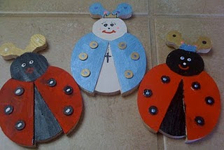 Two red wooden ladybugs and one blue wooden ladybug with a cross and crown