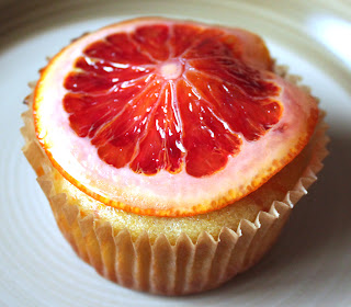 Vanilla cupcake with a blood orange slice on top of it