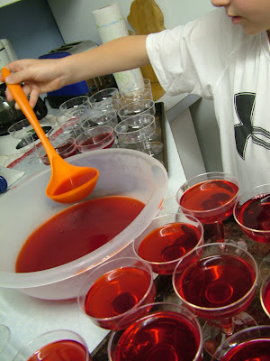 Red Jell-O being poured into plastic wine glasses