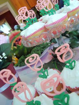 Display of cupcakes with white frosting and candy melt rose toppers