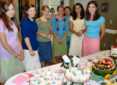 Women lined up in front of a table of baby shower food
