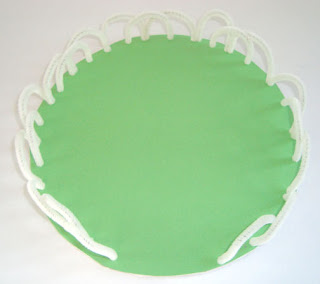 Finished green circle of construction paper and white pipecleaner fence