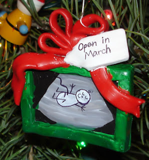 Ornament of a gift box with a baby inside reading "open in March"