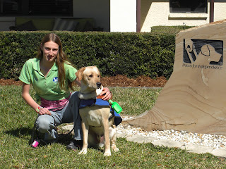Picture of Toby & I beside the SEGDI sign - Toby's wearing his harness & coat in a sit