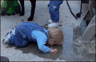 funny kids drinking water from puddle or pavement very odd photo