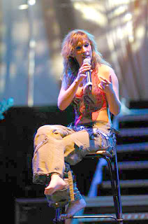 La cantante española Malú, se dirige a su publico sentada descalza sobre un taburete