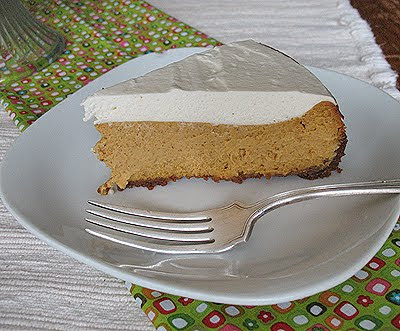 A slice of pumpkin cheesecake with rum whipped topping resting on a plate.