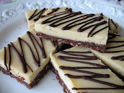 A close up photo of almond cheesecake bars stacked on top of each other.