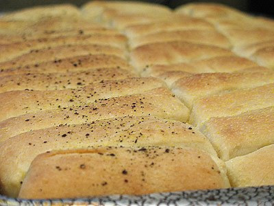 A close up photo of freshly baked pull apart cornmeal dinner rolls on a pan.