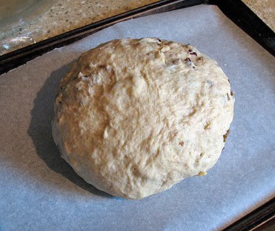 A photo of 2/3 of the artos dough resting on a baking sheet with parchment paper.