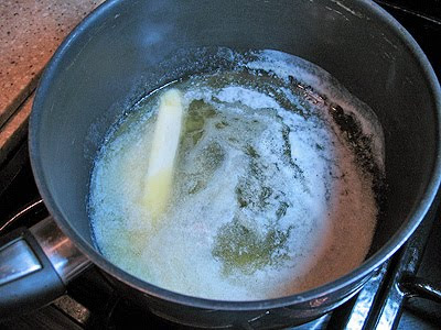 A close up photo of butter being melted in a saucepan.