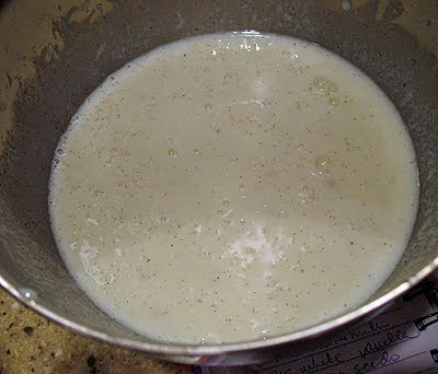 An overhead photo of buttermilk, egg whites, vanilla extract, and the vanilla bean seeds in a medium bowl.
