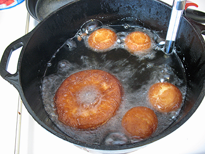 A photo of doughnuts being fried in a pan.